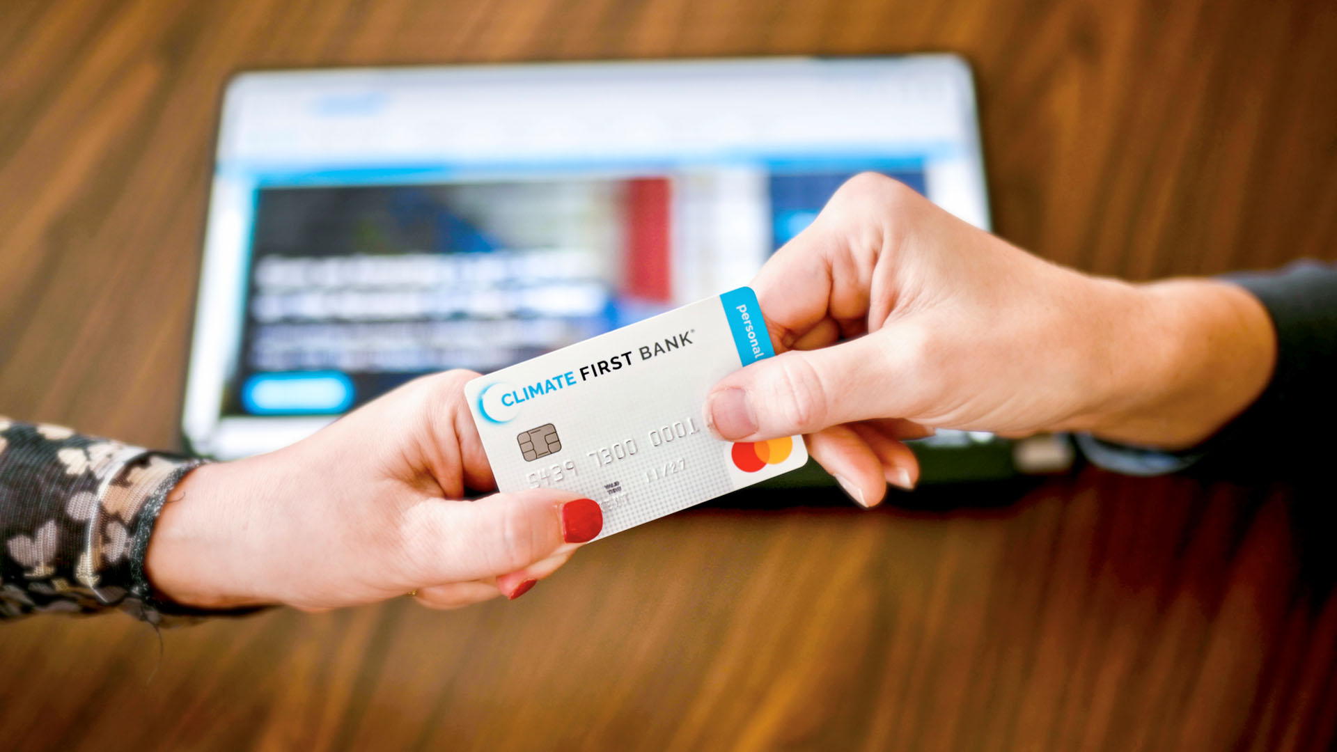 Two hands exchanging a Climate First Bank credit card.